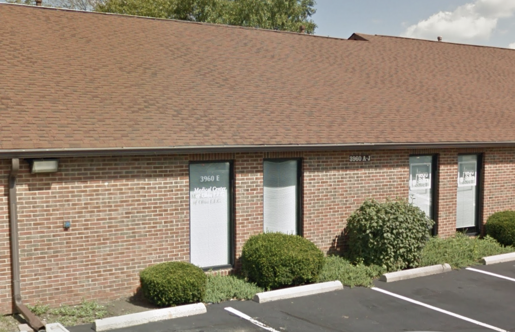 An image of the outside of the Knight Osteopathic healing center. A brick building connected directly to an asphalt parking lot.